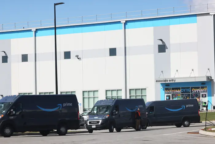 Amazon delivery vans are seen leaving the Amazon's JFK8 Staten Island fulfillment center.